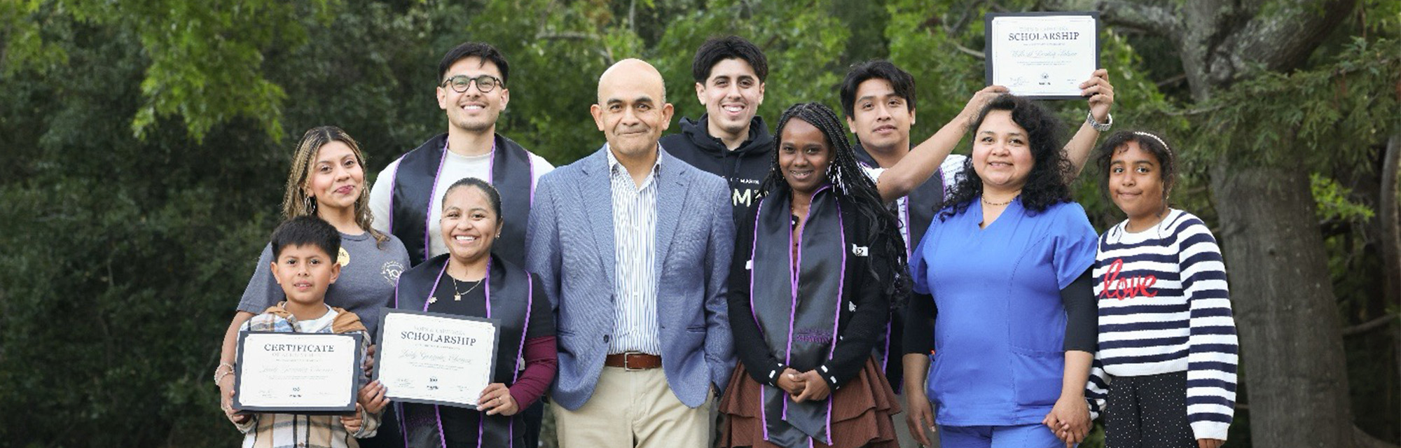 Group of students and supporters posing outdoors with scholarship certificates.